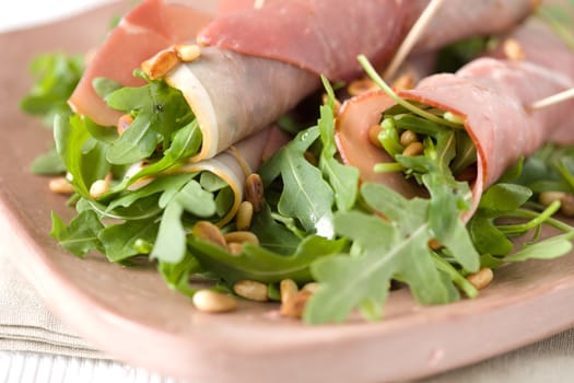 Appetizer with hamrolls, salad and pineseeds