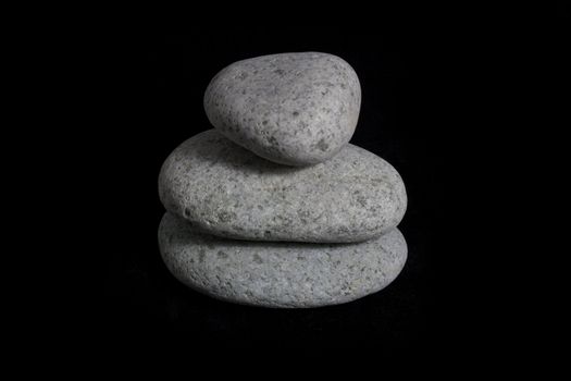 Stack of pebble stones against black background.