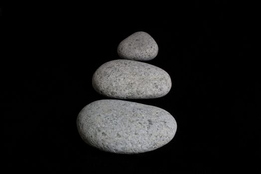 Three pebble stone form up an arrow against black background.