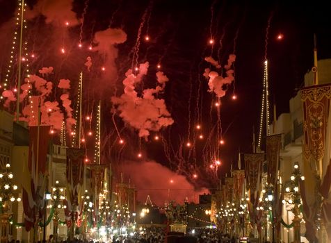 The sky is illuminated bright red by fireworks during the local village festa in the town of Zurrieq in Malta celebrating their patron saint St Catherine of Alexandria