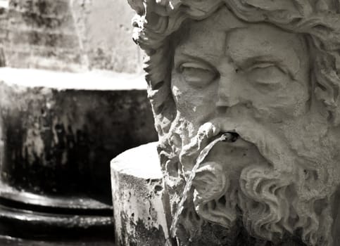 Highly eroded medieval statue in a fountain