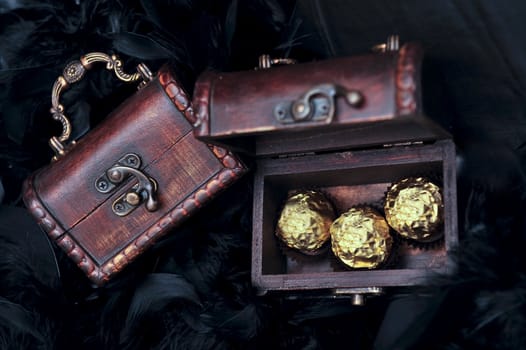 three sweets in mini small treasure chest next to closed chest