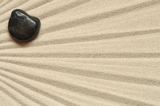 Abstract sand background with lines and black stone