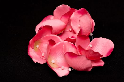 artificial pink petals and whitw glasses on black
