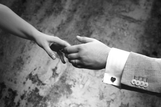 Female hands in man's hands on old wall background