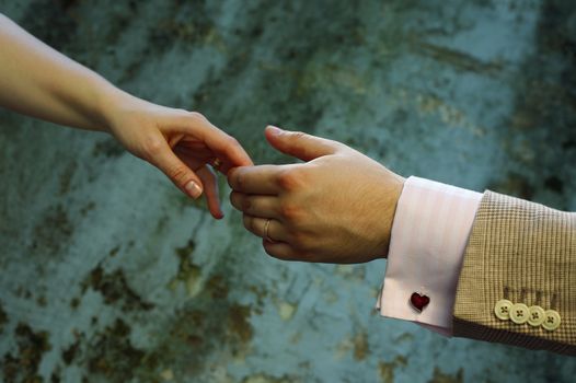 Female hands in man's hands on old wall background