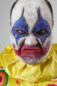 A nasty evil clown, angry and looking mean.