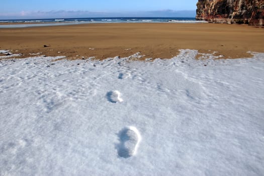 footprints on an empty beach on a cold winters day
