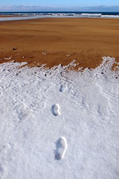 footprints on an empty beach on a cold winters day