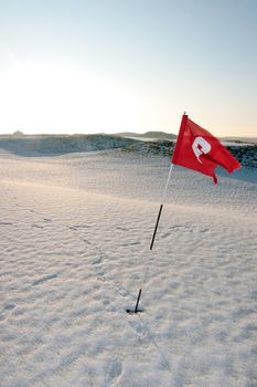 flag on a snow covered links golf course in ireland in winter
