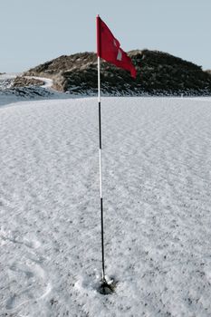 flag on a snow covered links golf course in ireland in winter