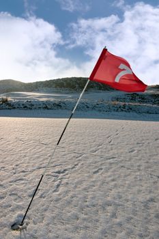 flag on a snow covered links golf course in ireland in winter