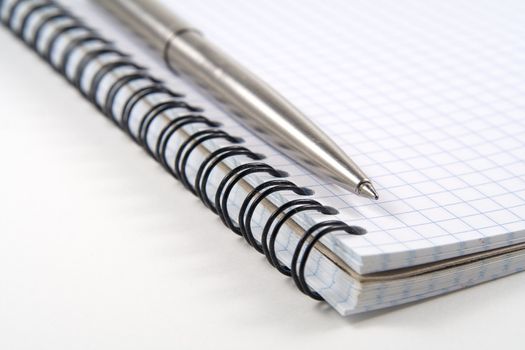 Pen on spiral notebook on white background. Shallow depth of field