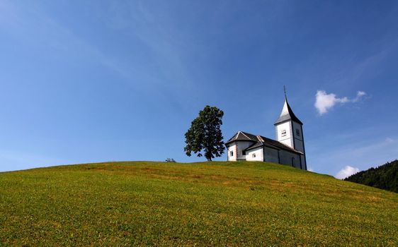 Lonely church and a tree on a hill