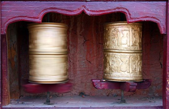 Two Tibetan Buddhist prayer wheels, one is in motion