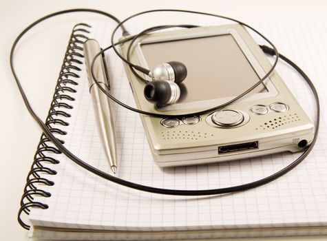 Pen and PDA with headphones on spiral notebook