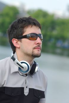 Young man with headphones on city view background looking at something