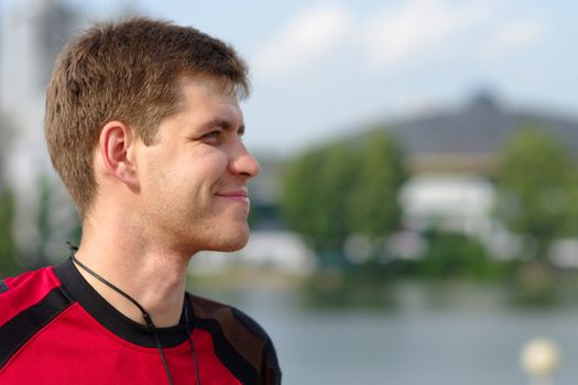 Young smiling sportsman on city view background looking at something