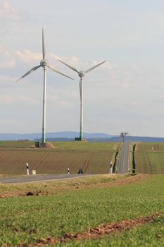 two wind turbines near a road in rural german landscape