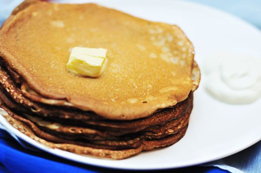 pile of pancakes on the plate with butter in soft selective focus