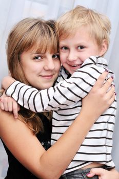  Brother and sister at home smiling and embracing
