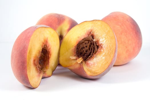 Three juicy peaches. Foreground one is divided in half