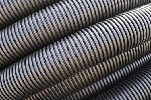 Close up of the pattern formed by a coil of black plastic pipework, suitable as abstract background.