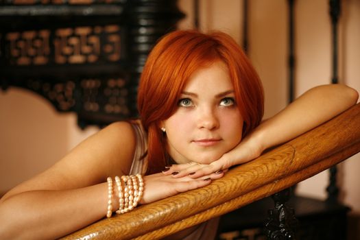 Portrait of the girl with red hair in an interior
