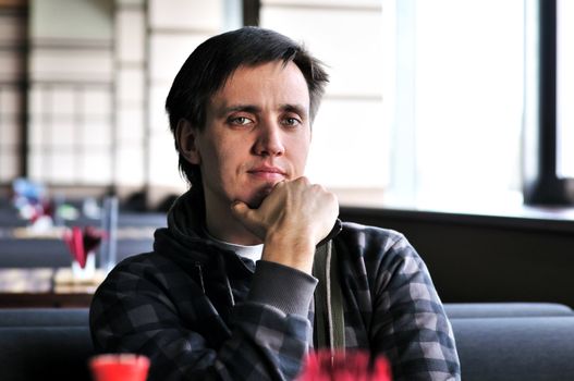 brunette man sitting in cafe next to the window