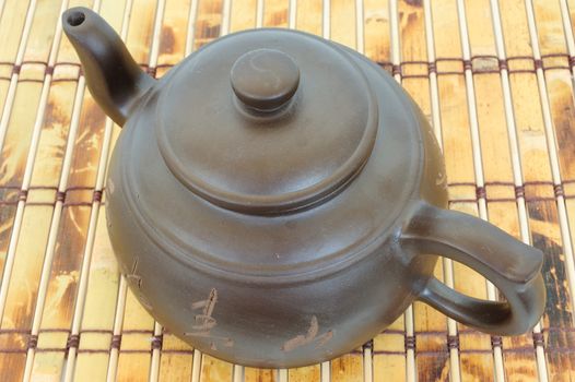 classic chinese teapot of brown clay over bamboo mat