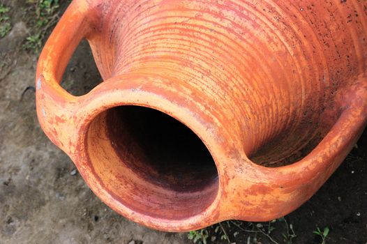 old-style greek amphora laying on earth
