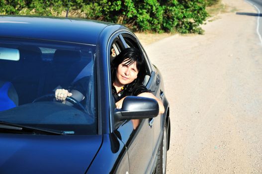 young brunette woman driving a blue car