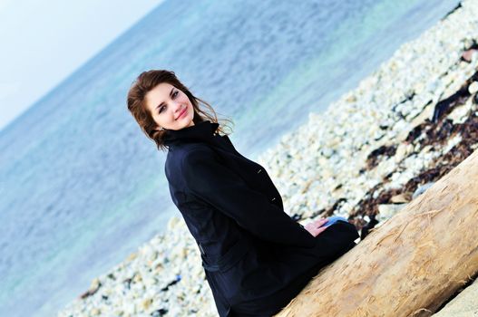girl on the beach sitting on the  log