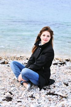 Beautiful young girl relaxing near the sea in spring time
