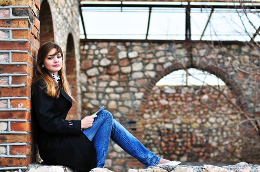 teen lovely girl reading near the brick wall