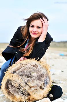 teen lovely girl on the beach sitting on the log
