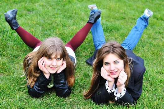 two lovely teen girls laying on the green grass