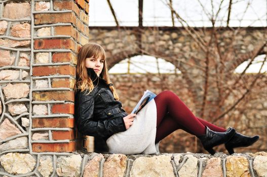 teen girl reading magazine outdoors on the window