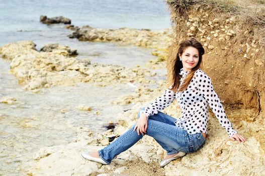  teen smiling girl wearing spotted blouse on the sea coast
