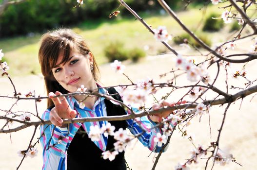 attractive young girl standing with first spring flowers of sakura
