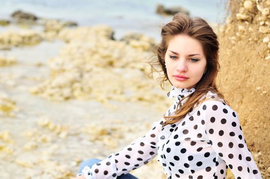 teen romatic girl wearing spotted blouse on the sea coast