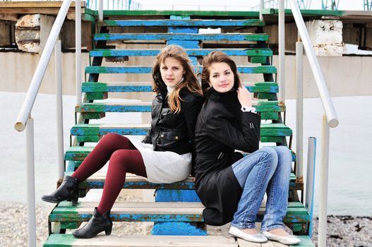   two teen lovely girls sitting on  the stairs
