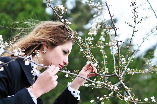 longhaired teen girl near the first spring blossom