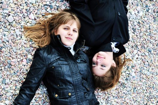 two lovely teen girls laying on the pebble in spring time

