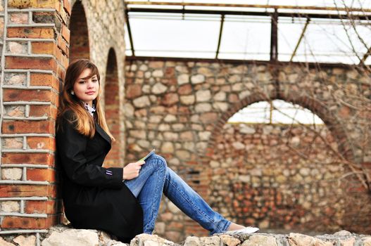 pretty teen girl reading  outdors on the brick window