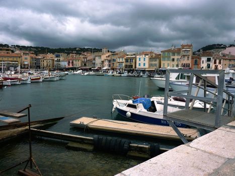 Port of Cassis with small boats and buildings by cloudy weather, France
