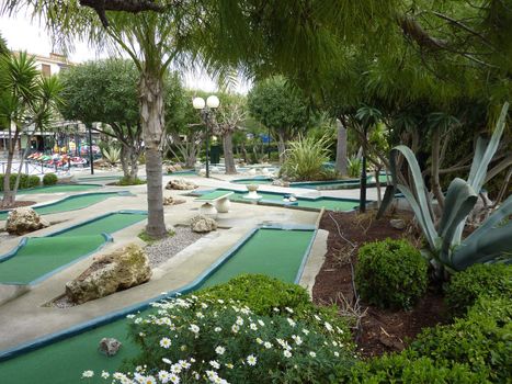 Green minigolf game among plants, trees and flowers