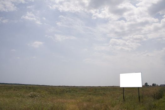 Empty field with white billboard on side of frame