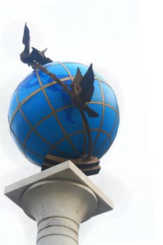 Close-up of a peace monument with doves flying around a blue globe