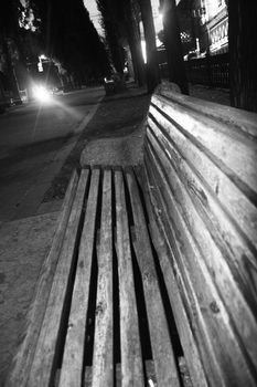 Black and white image of a bench in empty park